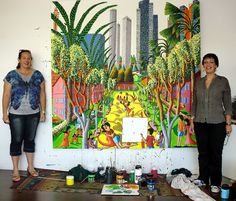 two women are standing in front of a painting