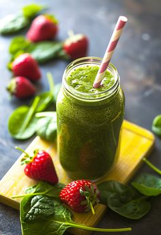 a green smoothie with strawberries and spinach leaves