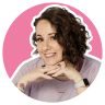 a woman with curly hair is smiling and posing for a photo in front of a pink circle