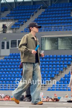 a man walking in front of an empty bleachers with blue seats behind him