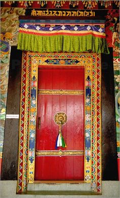 a red door with decorations on it and a green curtain hanging from the ceiling above