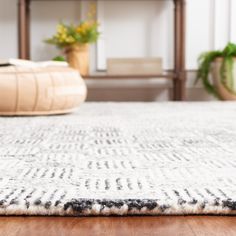 a white rug with black spots on it in front of a wooden shelf and potted plants