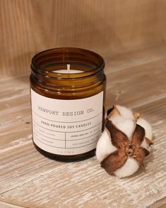 a candle sitting on top of a wooden table next to a cotton ball and a flower