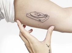 a woman's arm with a record player tattoo on it