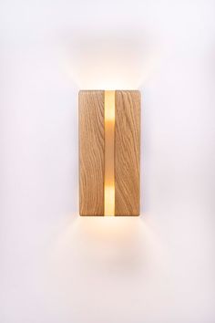 a wooden square light fixture mounted on a white wall with a gold strip around it