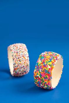 two sprinkle covered donuts on a blue surface