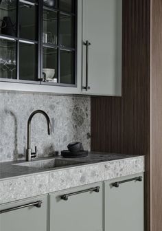 a kitchen with green cabinets and marble counter tops, along with a stainless steel faucet