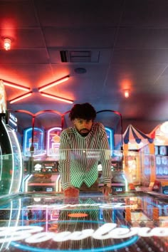 a man sitting on top of a glass table in a room filled with neon lights