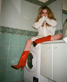 a woman sitting on top of a washing machine