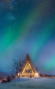 an image of a building that is under the night sky with aurora lights in the background