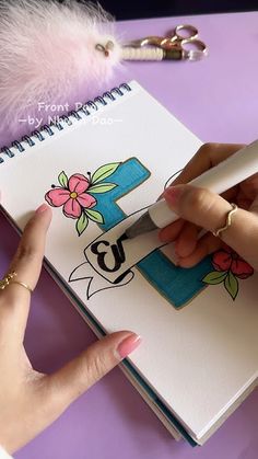 a hand holding a pen and writing on a notebook with the letter e in it