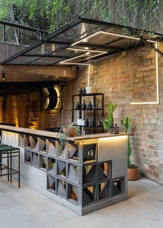 an outdoor bar area with brick walls and green plants on the roof, surrounded by greenery