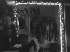 the closet is filled with clothes and other items in black and white, as well as fairy lights