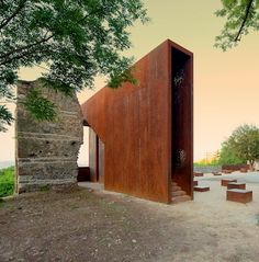 the building is made out of metal and has benches in front of it, along with trees