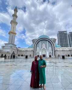 two people standing in front of a large building