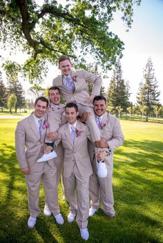 a group of men standing next to each other on top of a lush green field