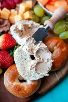 an assortment of fruits and bagels on a platter with a knife in the middle