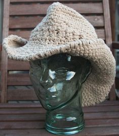 a crocheted hat sitting on top of a glass head