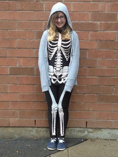 a woman in skeleton costume standing next to a brick wall with her hands on her hips