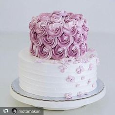 two tiered white cake with pink frosting flowers on top, sitting on a plate