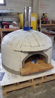 a large round oven sitting on top of pallets in a room filled with other items