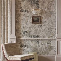 a chair sitting in front of a wall with flowers on it