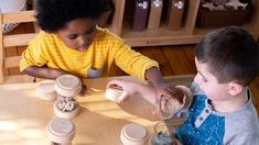 two children sitting at a table with jars and starfish