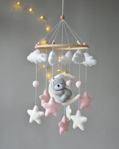 a teddy bear sitting on top of a cloud with stars hanging from it's sides