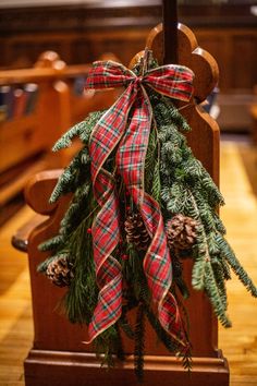 a wooden cross decorated with pine cones and plaid ribbon is on the alter at a church