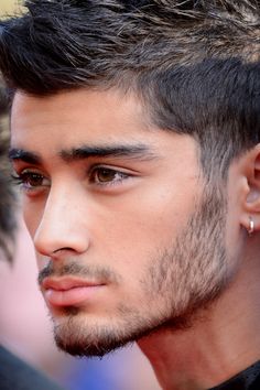 a close up of a person with short hair and piercings on his ear, wearing a black shirt