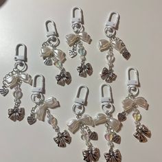 several charms are shown on a white surface, one is silver and the other is clear