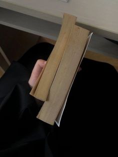 a person is holding some wood in their hand while sitting at a desk with a laptop on it