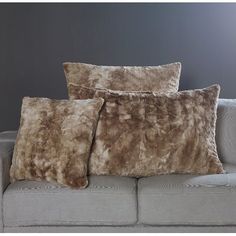 two pillows sitting on top of a couch in front of a gray wall and floor