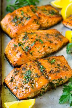 grilled salmon with herbs and lemons on a baking sheet