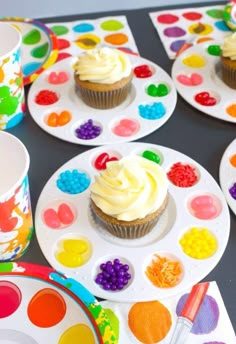 cupcakes with white frosting on colorful plates and paint splattered napkins