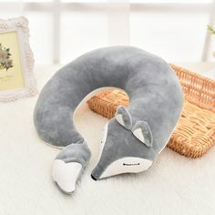 a gray and white stuffed animal pillow sitting on top of a table