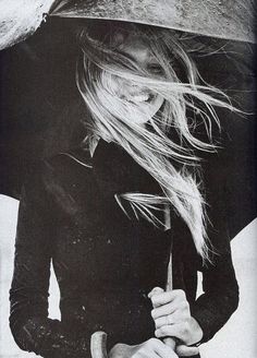 a woman holding an umbrella while standing in the rain with it's wind blowing her hair