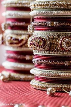 several bracelets are stacked on top of each other, with red and gold accents