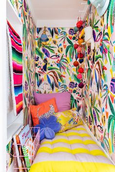 a bedroom with colorful wallpaper and lots of pillows