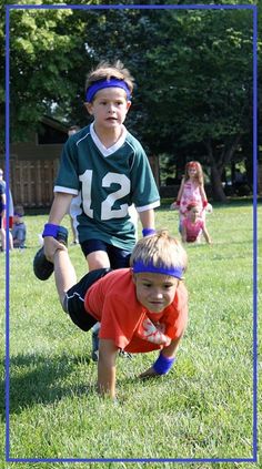 two young boys are playing football in the grass with their hands on each other's hips