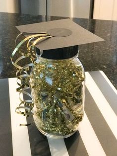 a graduation cap sits on top of a jar filled with confetti and streamers