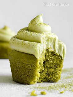 a green cupcake with white frosting on top