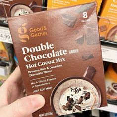 a person holding up a chocolate drink in front of some other drinks for sale at a store