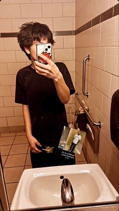 a man taking a selfie in a bathroom mirror with his cell phone up to his face