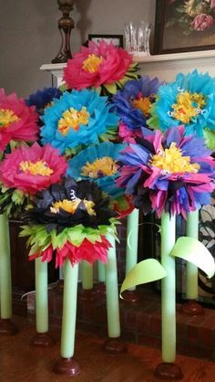 colorful paper flowers are in vases on the table