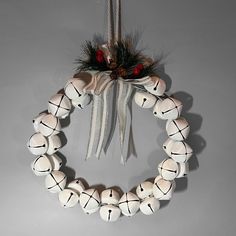 a wreath made out of white balls hanging from a string and decorated with pine cones