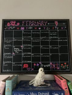 a stuffed owl sitting on top of books in front of a chalkboard with writing