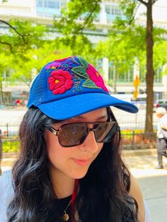 Hand-embroidered in Chiapas, Mexico, these Floral Caps are one-of-a-kind and masterfully crafted pieces. The cap features a vibrant array of flowers, perfect for bringing a pop of color and a touch of style to your look! Perfect for summer, this beautiful cap features a mesh rear for breathability and also has an adjustable head strap! Summer Festival Baseball Cap, Spring Summer Trucker Hat, Summer Festival Snapback Cap, Summer Festival Snapback Hat, Adjustable Summer Festival Baseball Cap, Adjustable Snapback Hat For Summer, Spring Floral Print Cap, Blue Summer Vacation Baseball Cap, Blue Baseball Cap For Summer Vacation