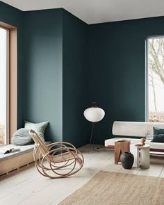 a living room with teal walls and white furniture in the corner, including a rocking chair