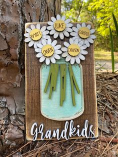 a wooden sign with flowers on it that says grandkids next to a tree